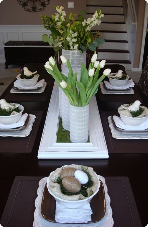 Spring Tablescape: Faux moss blanket in a white shutter (?), Yarn & string wrapped plastic eggs, set in bowls lined with burlap & more moss. Lots of fresh white flowers.